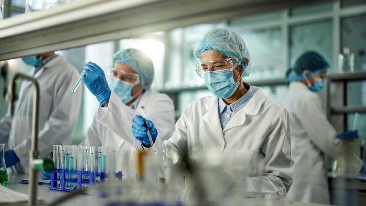 Professional pharmaceutical research laboratory with scientists performing quality control testing