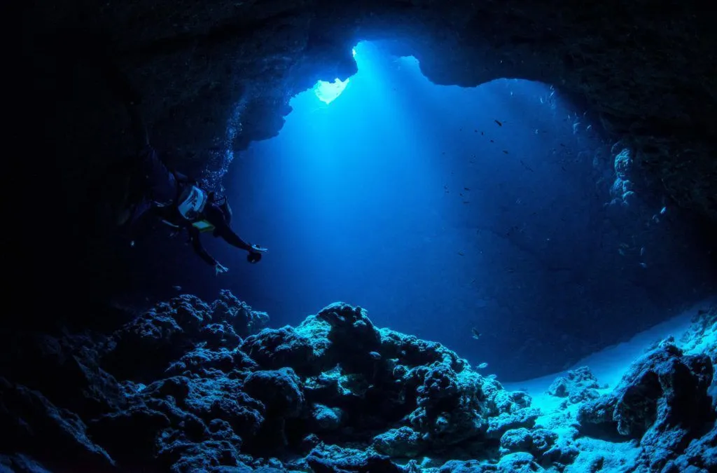 Vista subaquática da Fossa das Marianas com luz azulada penetrando as profundezas do oceano Pacífico