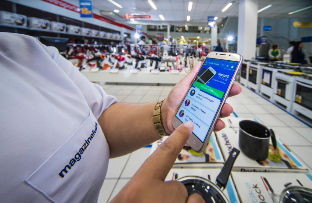 Cliente usando aplicativo da Magazine Luiza em smartphone dentro de loja física