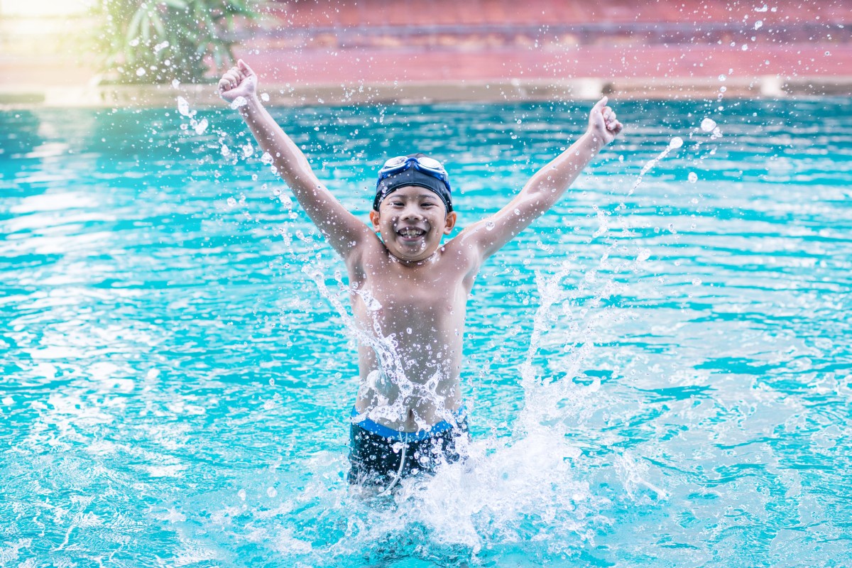Excited child splashing in pool during swim lesson