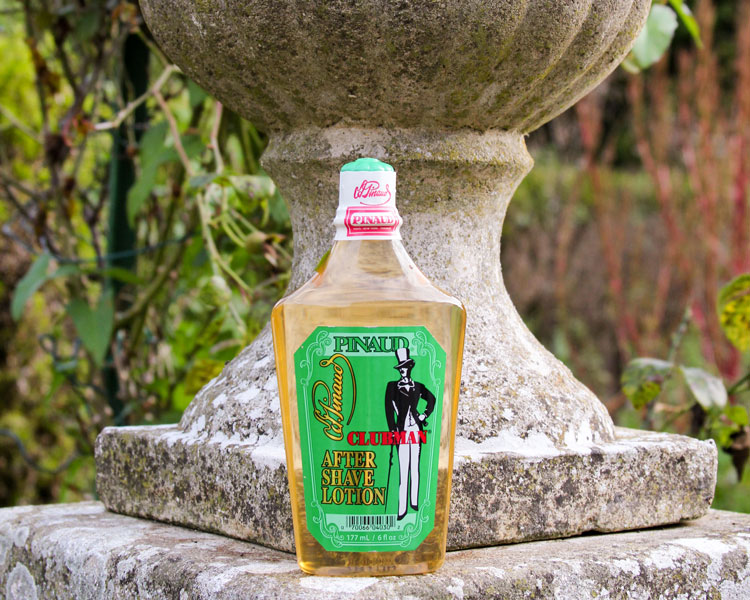 Vintage Pinaud Clubman aftershave bottle displayed on stone pedestal in garden setting