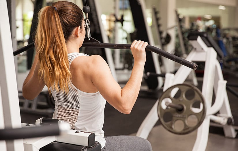 Person performing lat pulldown exercise on gym machine with focus on scapular retraction