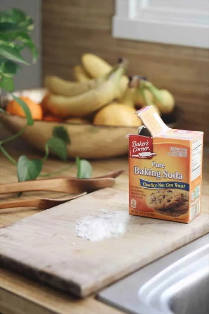 Baking soda sprinkled on wooden cutting board to deodorize onion smell