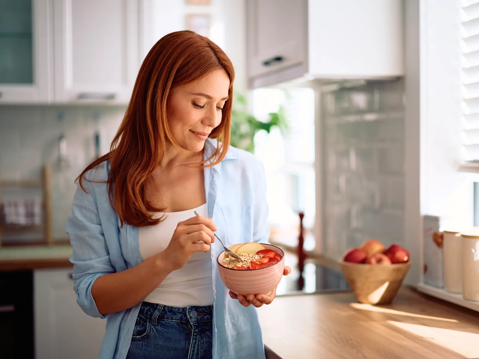 Woman eating healthy high protein breakfast bowl in bright kitchen