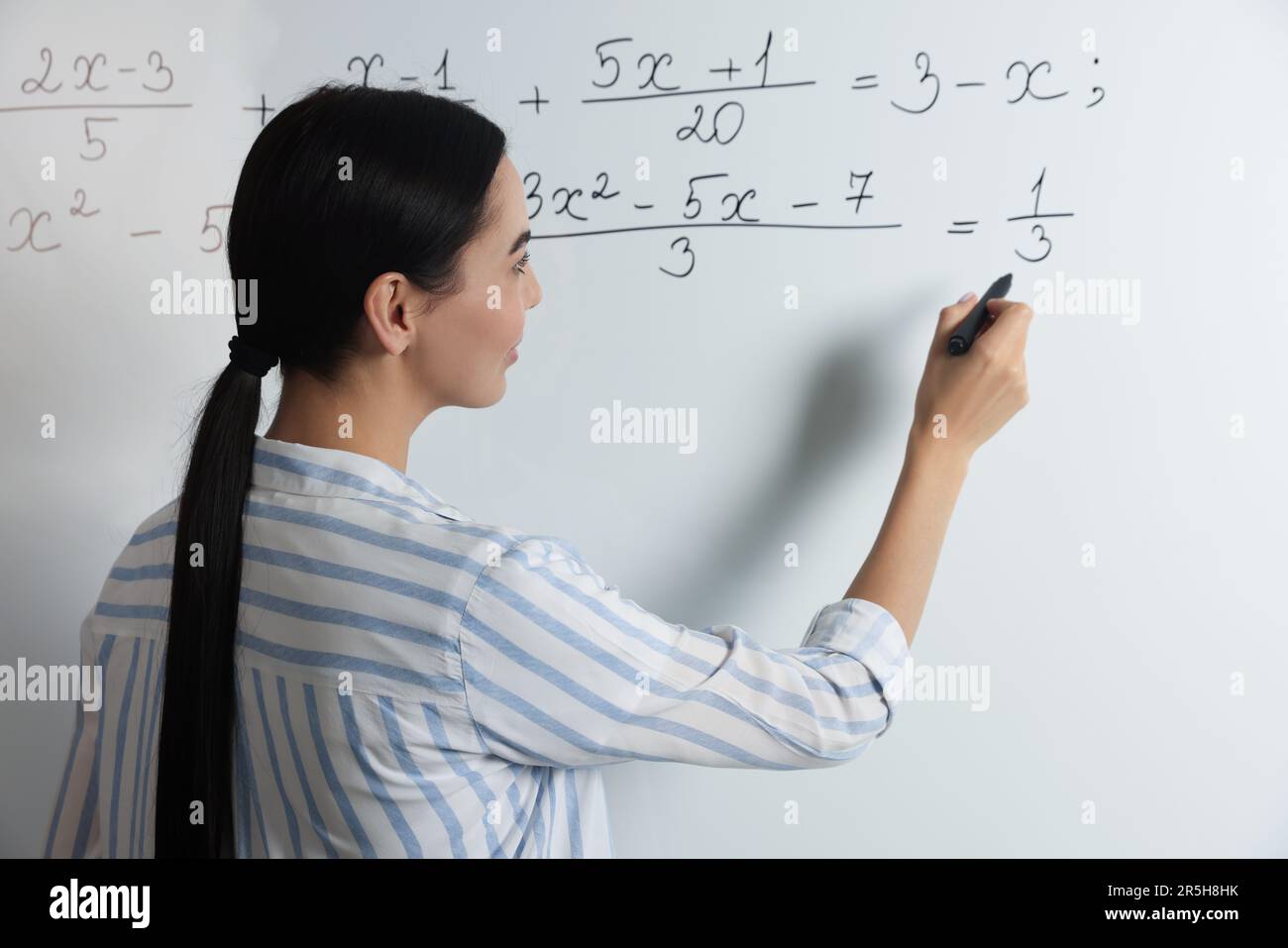 Math teacher explaining algebra equations on whiteboard step by step