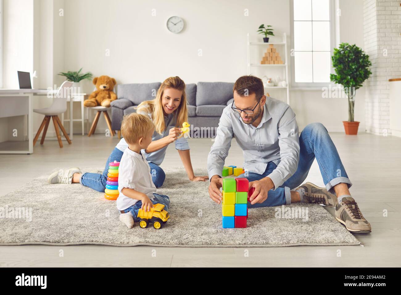 Mom and dad play with their son at home with a variety of toys and colored  cubes sitting in a room Stock Photo - Alamy