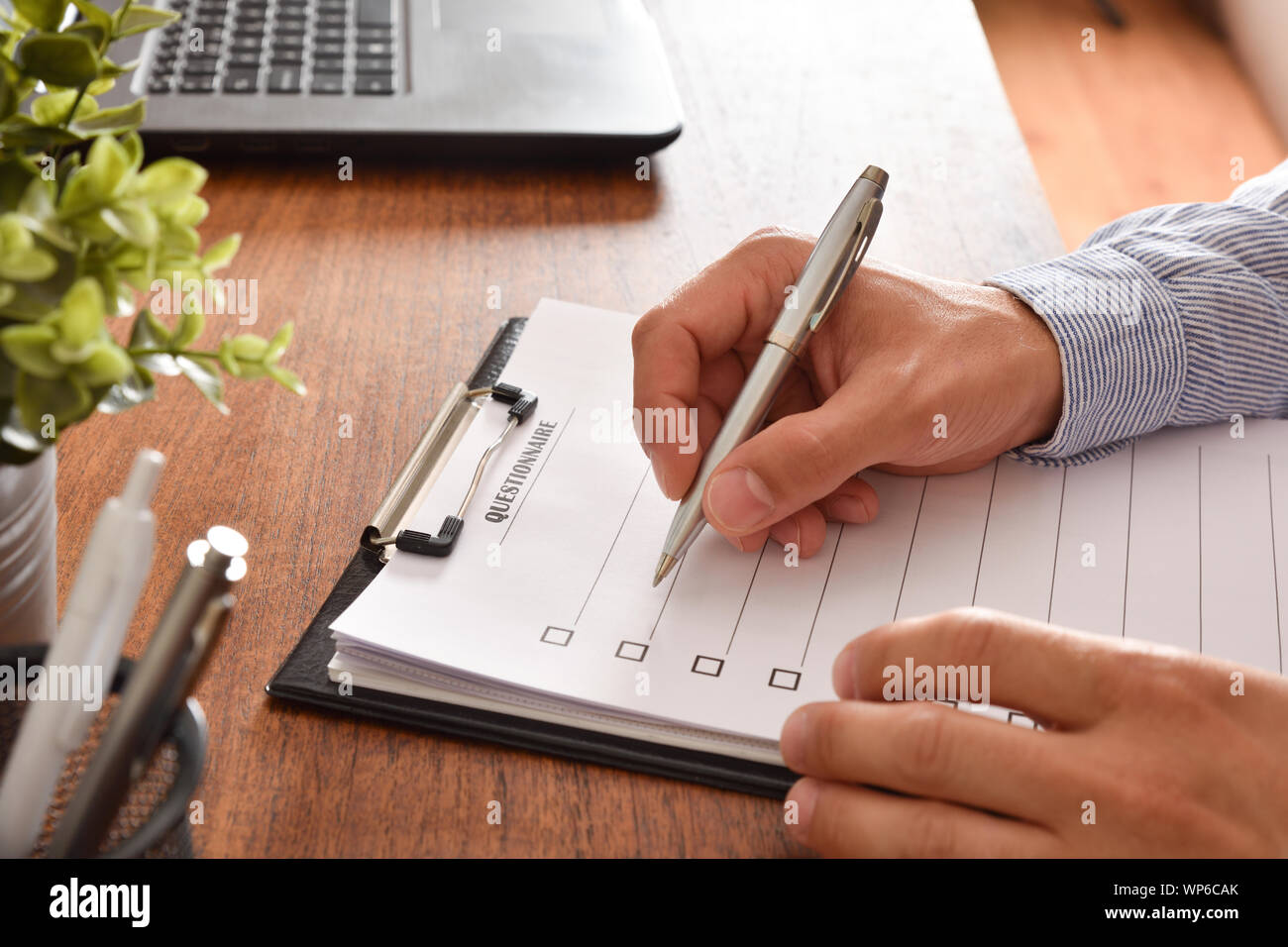 Man filling out a questionnaire on a wooden table. Horizontal composition.  Elevated view Stock Photo - Alamy