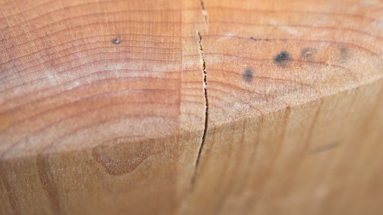 Close-up of a cracked wooden cutting board showing deep split in the wood grain before restoration repair