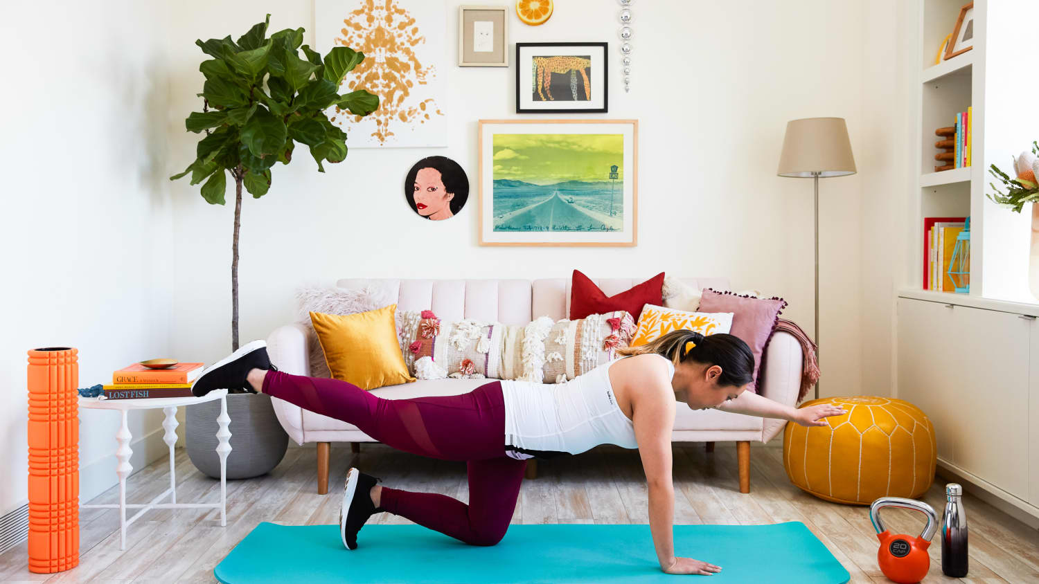 Woman performing a bird dog exercise on a yoga mat in a bright decorated living room