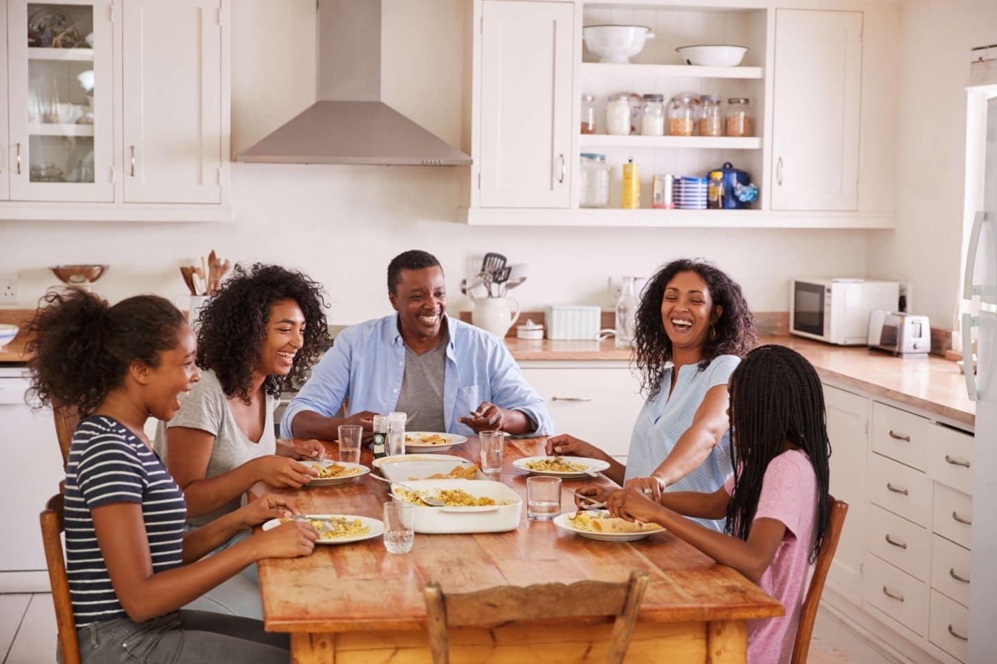 Família reunida em volta da mesa de jantar rindo e conversando, sem celulares à vista, representando a reconquista de momentos genuínos de conexão humana