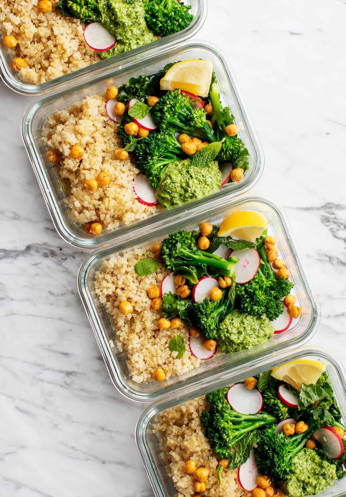 Healthy meal prep containers with quinoa, broccoli, chickpeas, and fresh vegetables