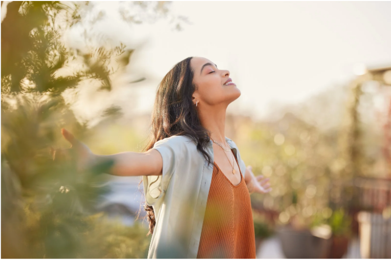 Outdoor Wellness and Gut Brain Connection Woman relaxing outdoors with arms open enjoying nature and wellness