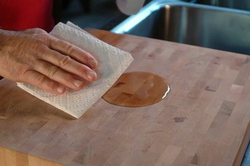 Applying beeswax cream to seal wooden cutting board