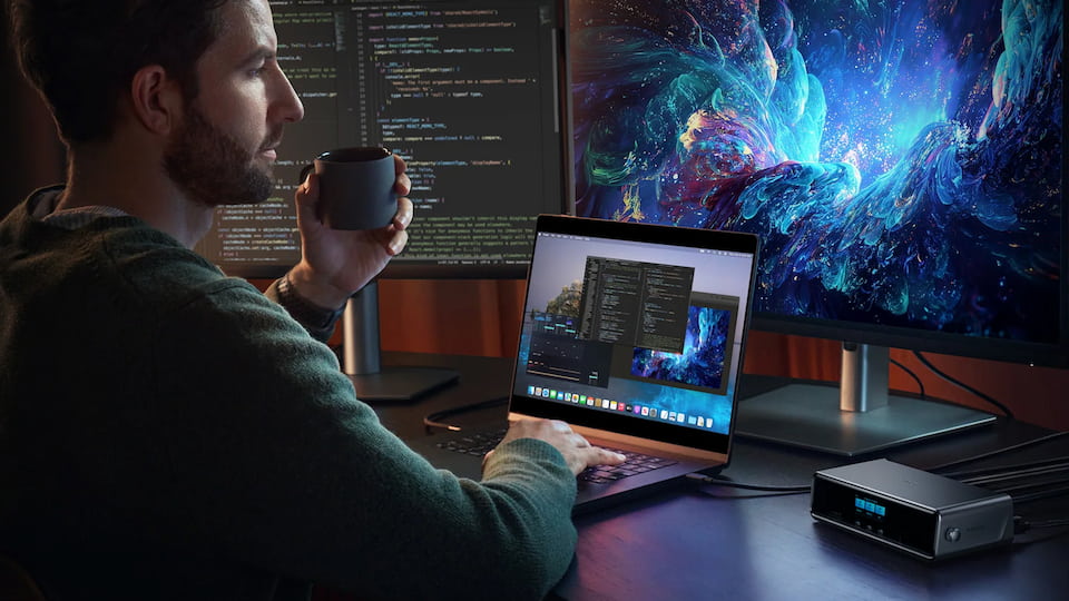 Man working at a clean minimalist desk setup with multiple monitors and laptop
