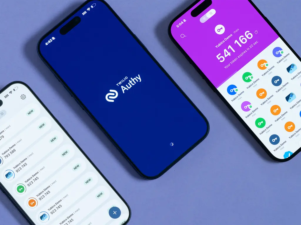 Overhead view of three smartphones displaying authenticator apps with 2FA verification codes