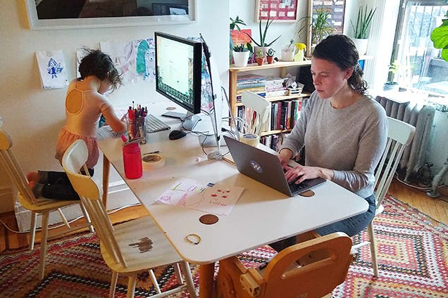 Parent and child working together at shared home office desk with laptops