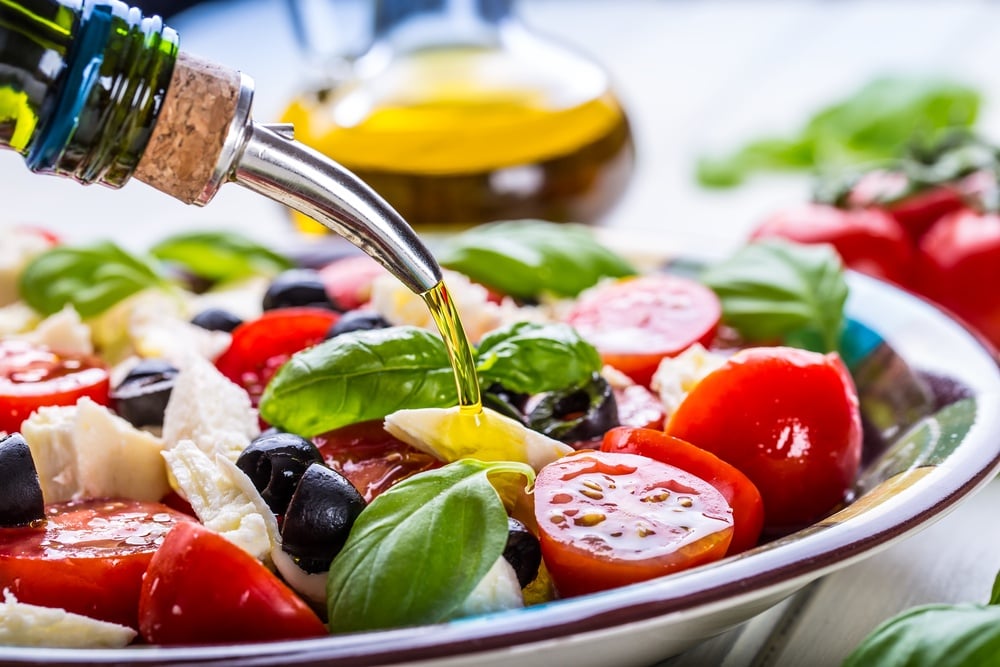 Mediterranean diet ingredients including olive oil, vegetables and nuts on table