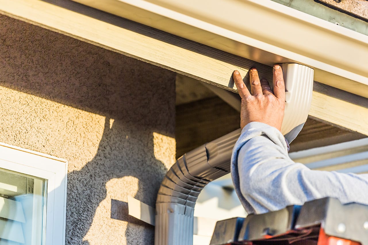 Professional gutter installer attaching a downspout