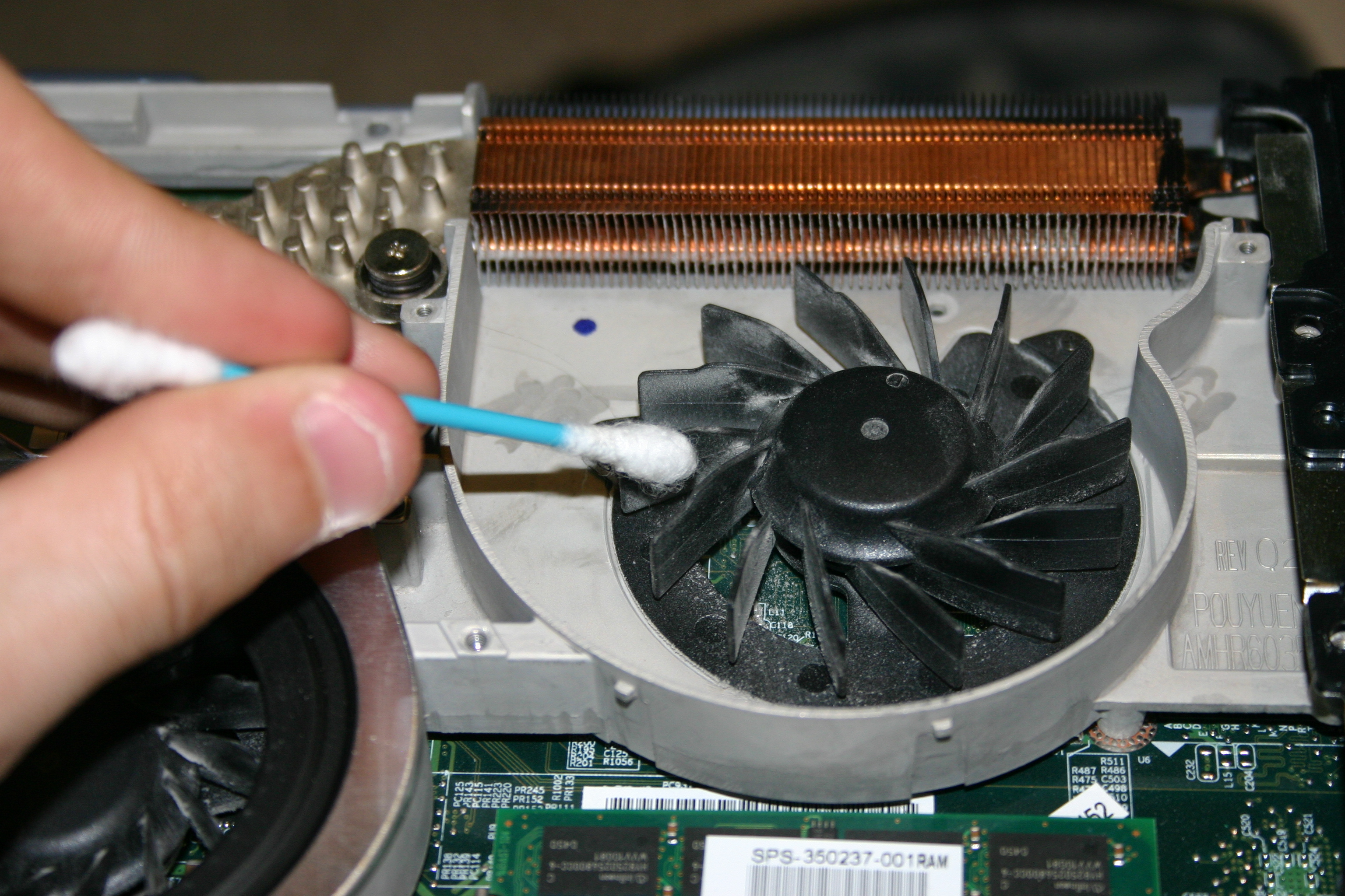 Laptop cooling system maintenance to prevent overheating Cleaning laptop cooling fan with cotton swab for better airflow