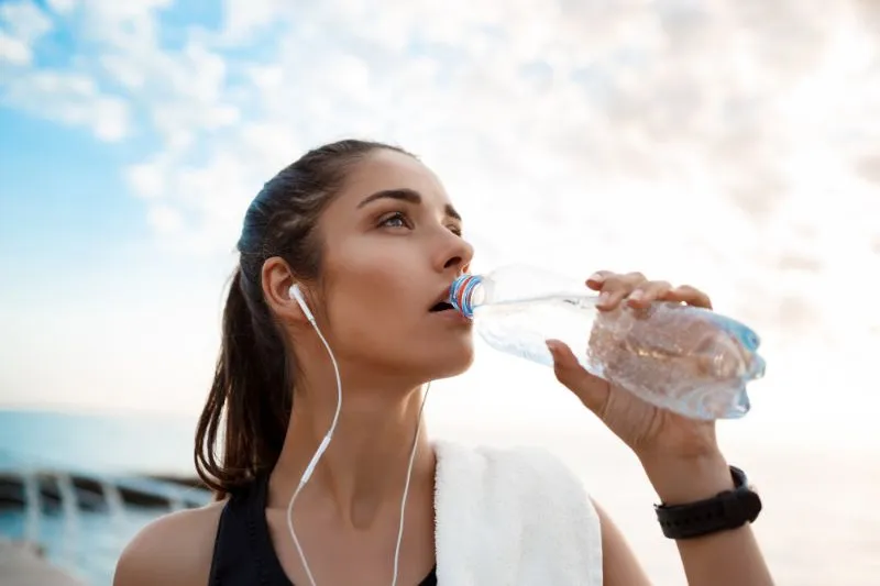 Woman drinking water after exercise outdoors