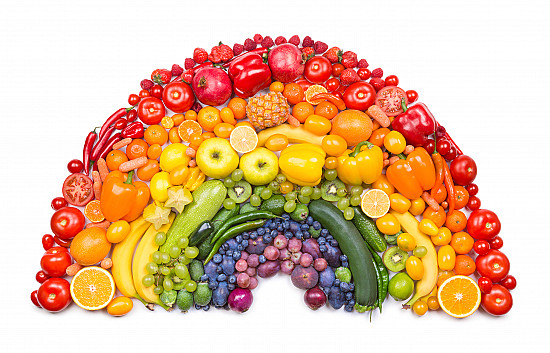 Rainbow of colorful fruits and vegetables arranged in an arc shape