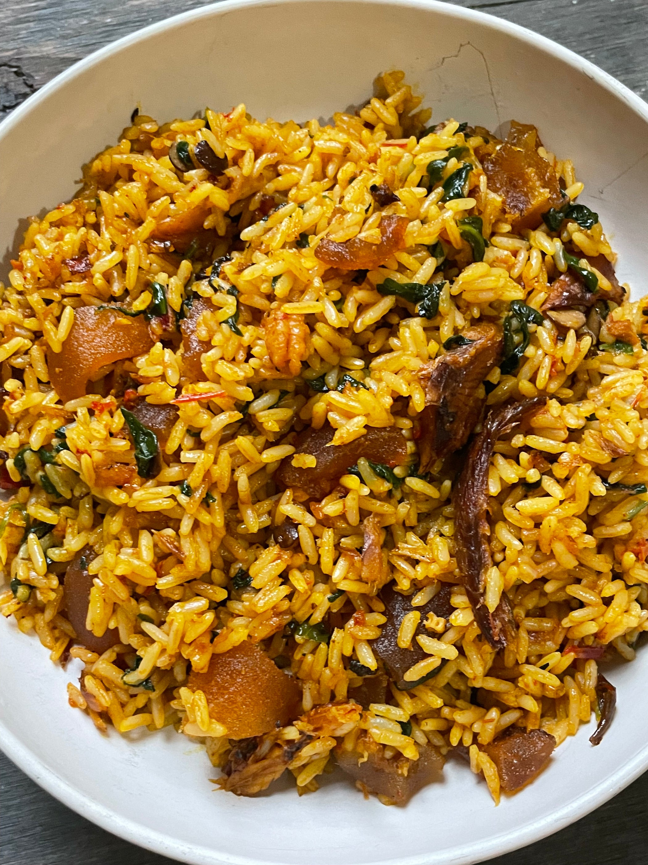 Native jollof rice made with long grain rice, red palm oil, crayfish, smoked fish, assorted meat, tomatoes and leafy greens - RoyalRoom Restaurant Lagos