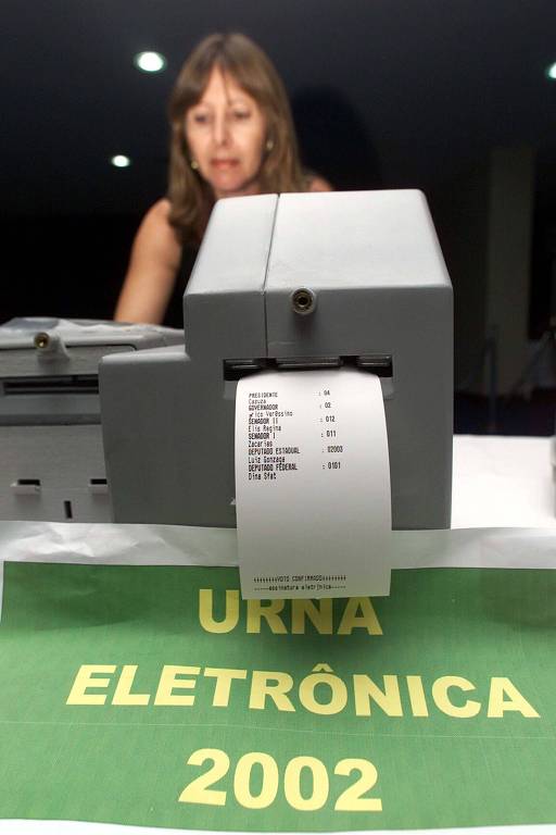 Urna eletrônica de 2002 com teste de voto impresso, mostrando comprovante de papel sendo emitido