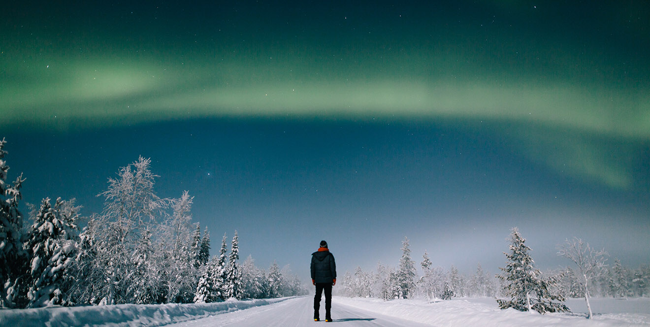 Aurora boreal sobre paisagem nevada na Finlândia com silêncio e tranquilidade