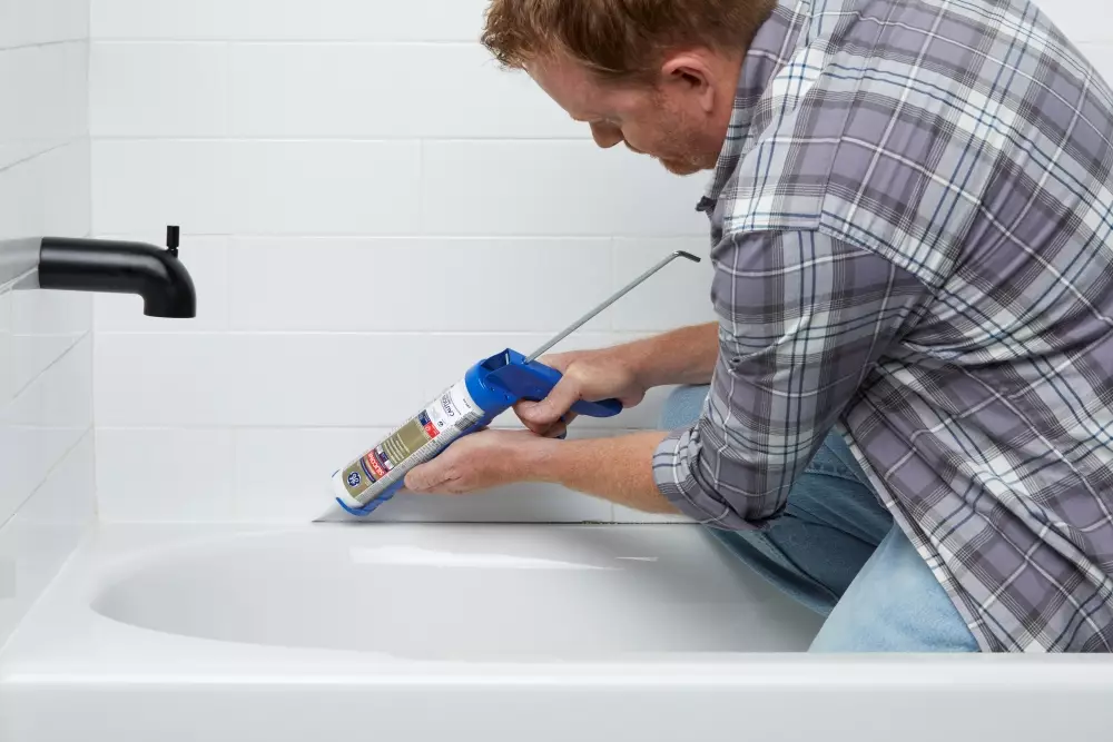 Contractor applying silicone sealant around bathtub