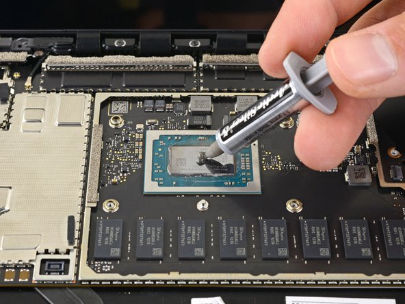 Applying new thermal paste to laptop CPU using syringe applicator during repaste process