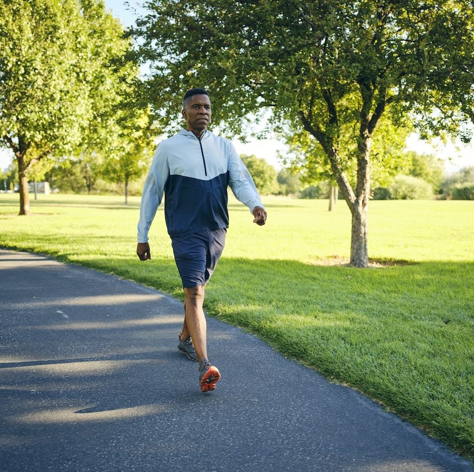 Man walking on outdoor path in park for daily exercise and healthy movement