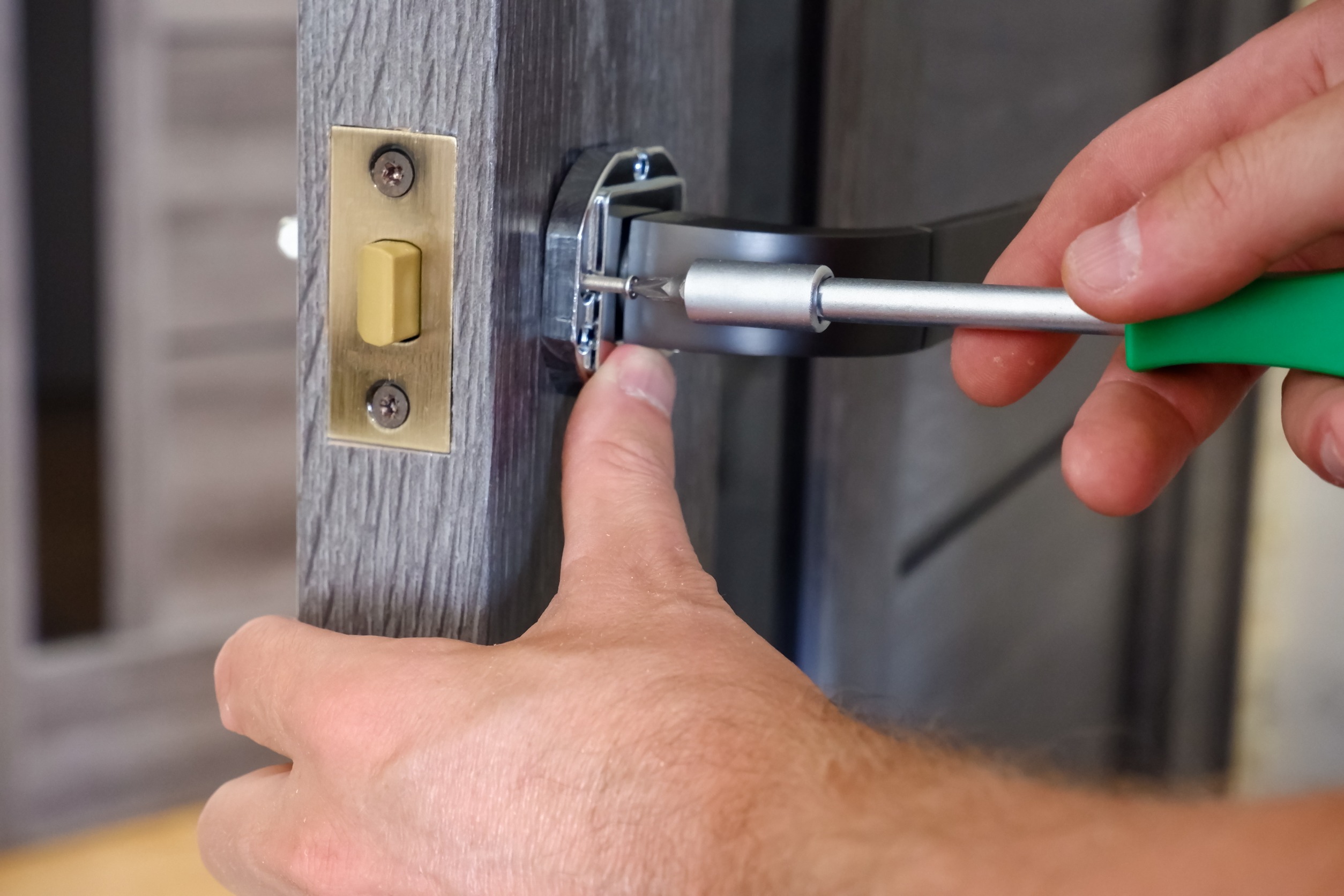 Handyman repairing door lock with screwdriver