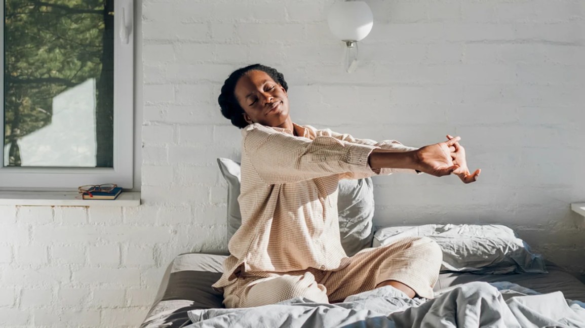Person doing gentle morning stretches on a bed in a bright room Person doing gentle morning stretches on a bed in a bright room