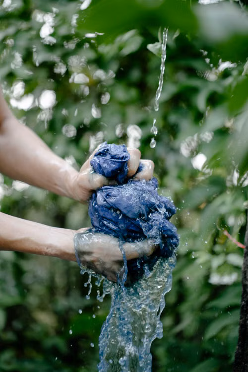 Hands Washing Clothes in Water Basin Outside