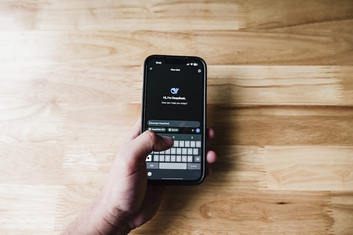 Person chatting with AI assistant on smartphone in a clean workspace