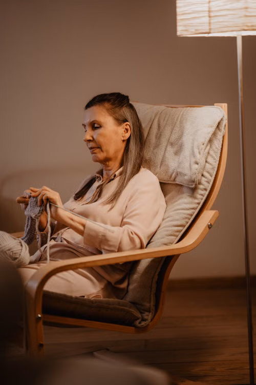 Woman Sitting on Wooden Rocking Chair Doing Crochet