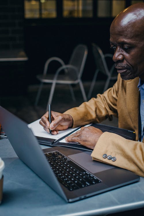 Focused African entrepreneur writing on laptop in cafe