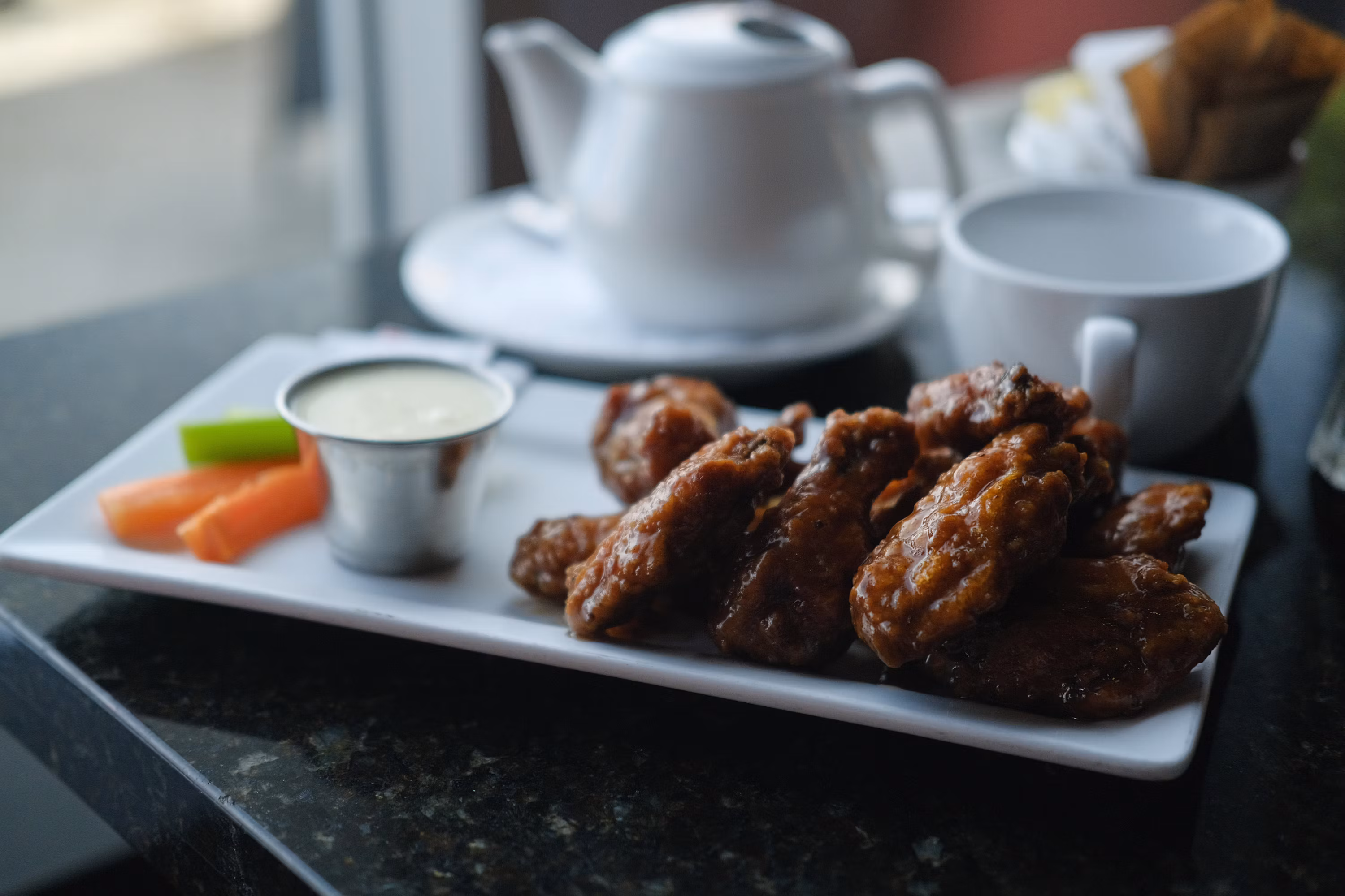 Plate of chicken wings with dipping sauce and vegetables restaurant style