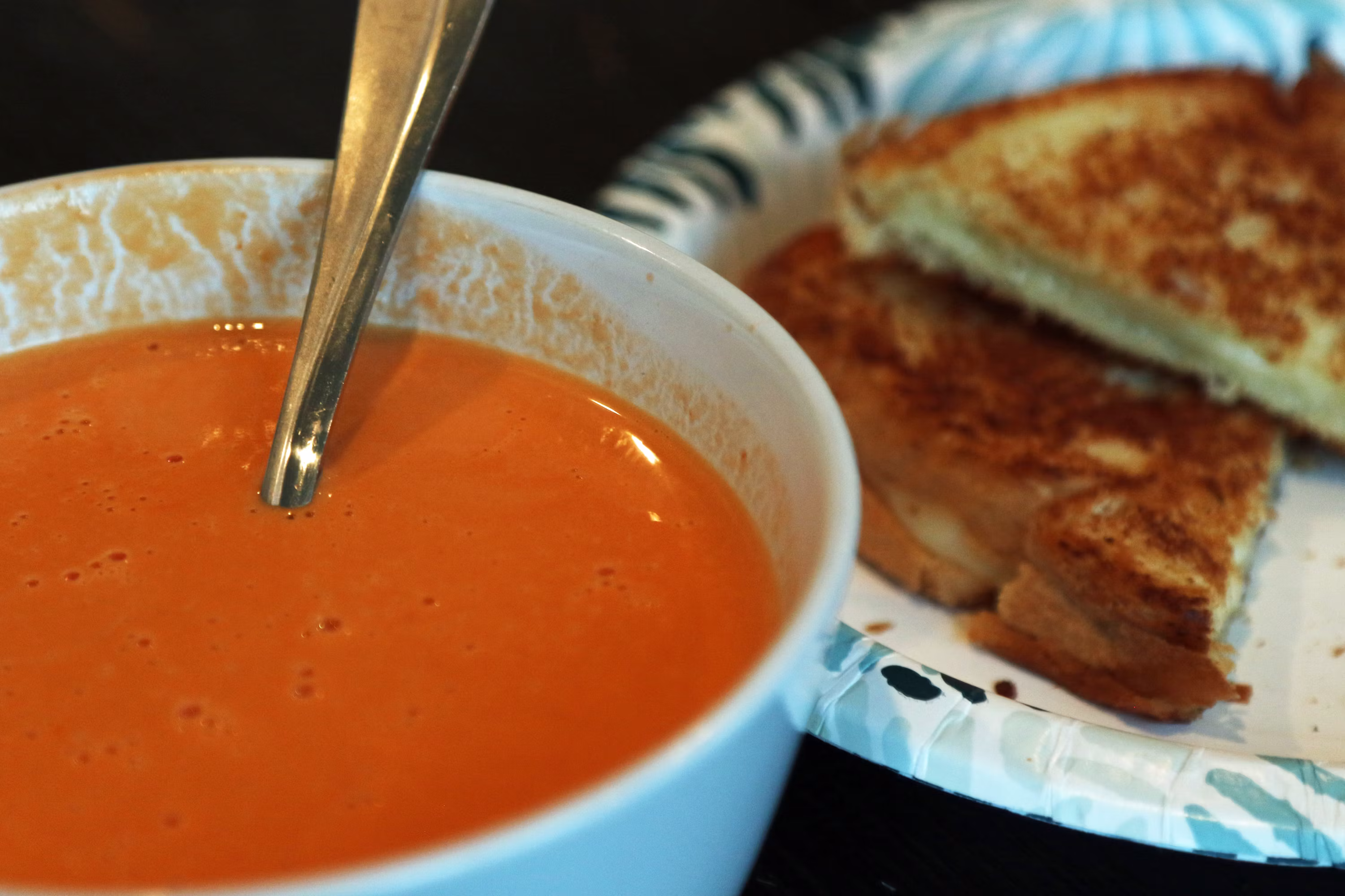 Tomato soup in bowl with grilled cheese sandwich