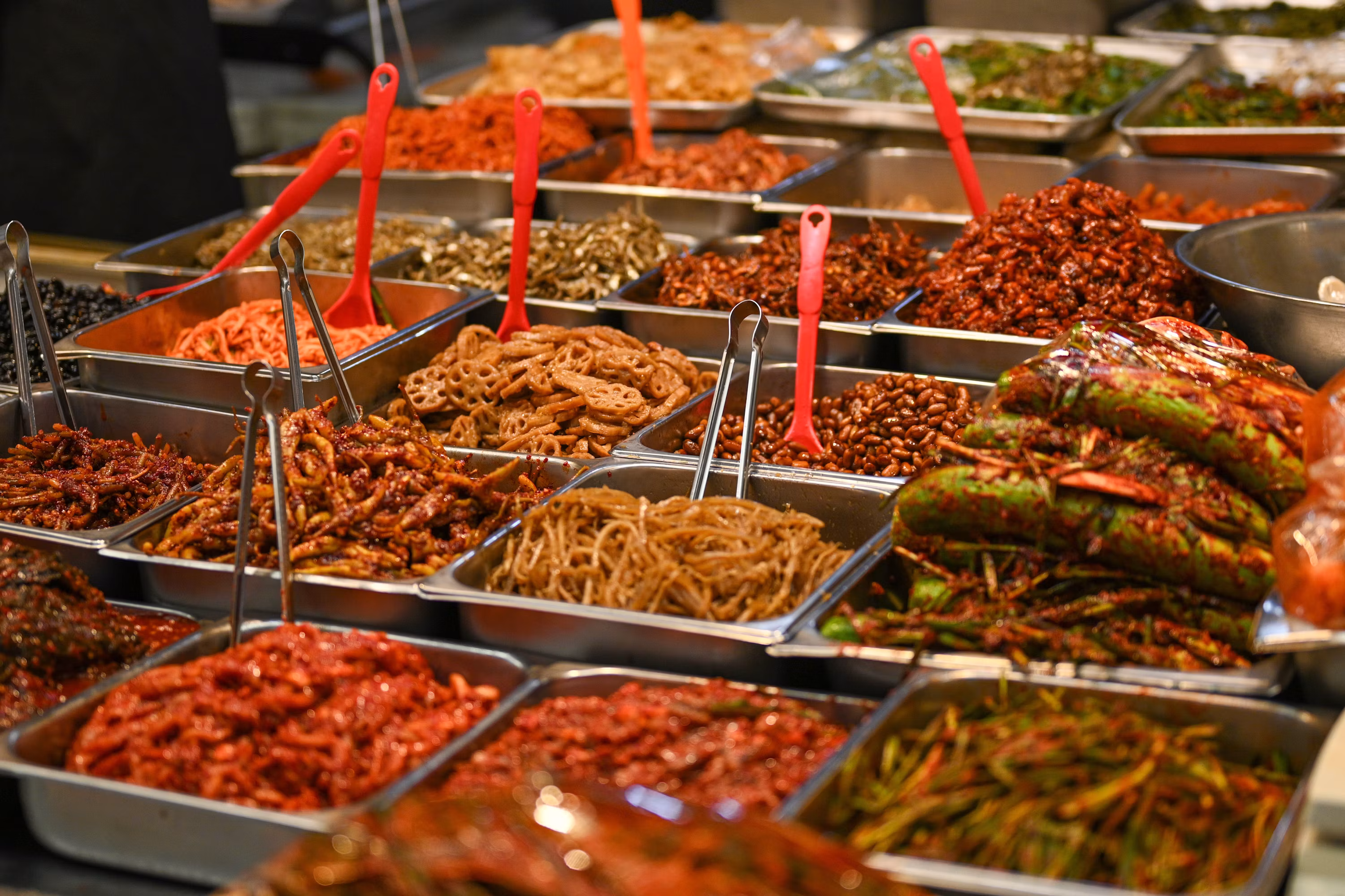 Colorful Korean banchan side dishes at market with red spoons