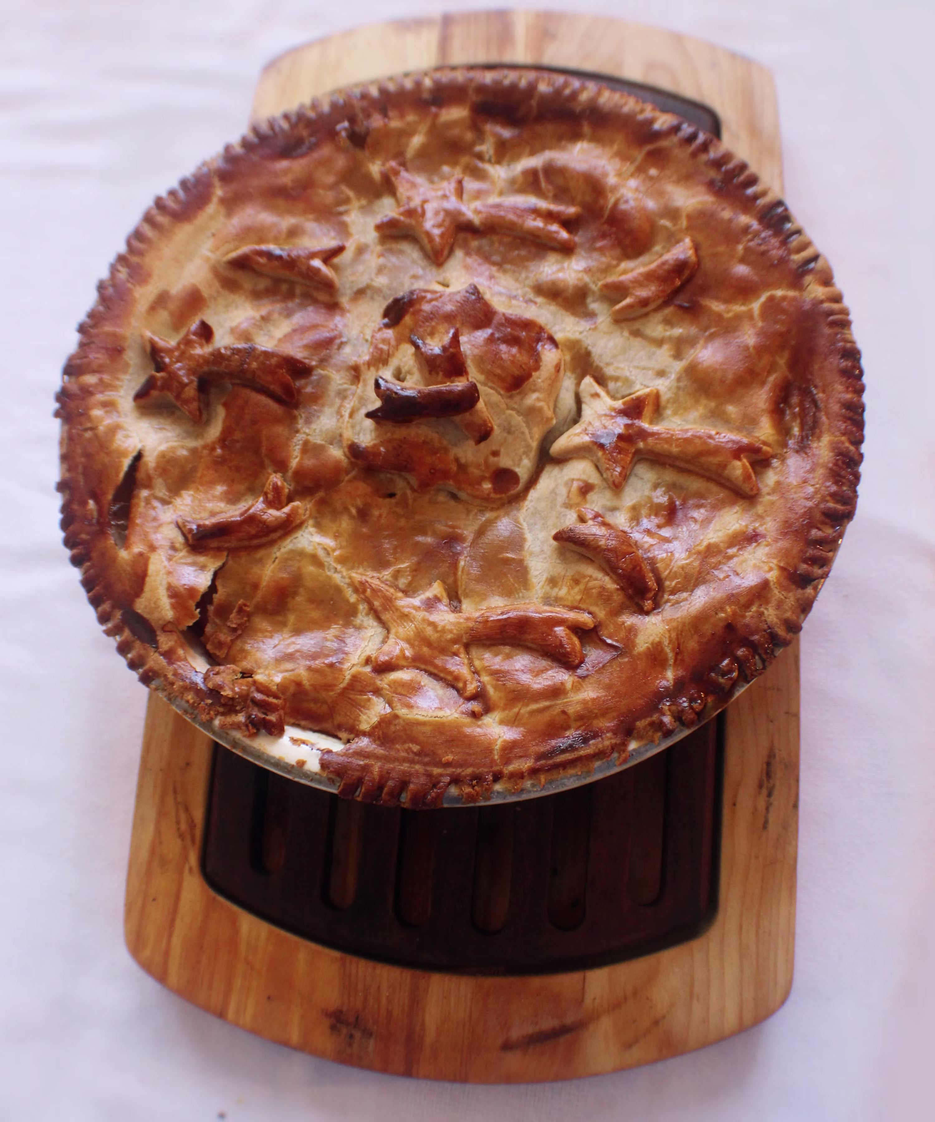 Golden decorative chicken pot pie with star crust on wooden board