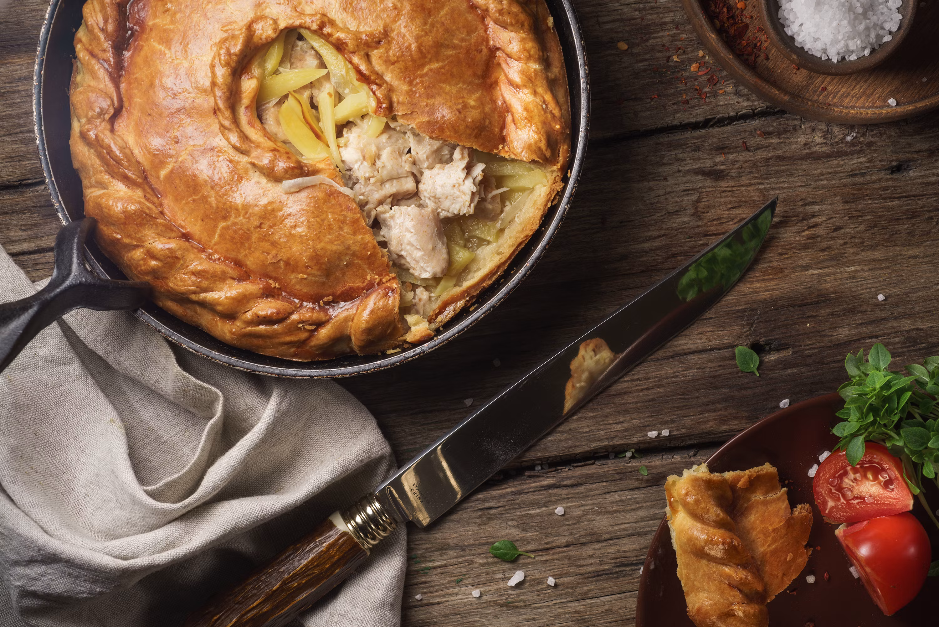 Golden chicken pot pie in cast iron skillet with flaky crust