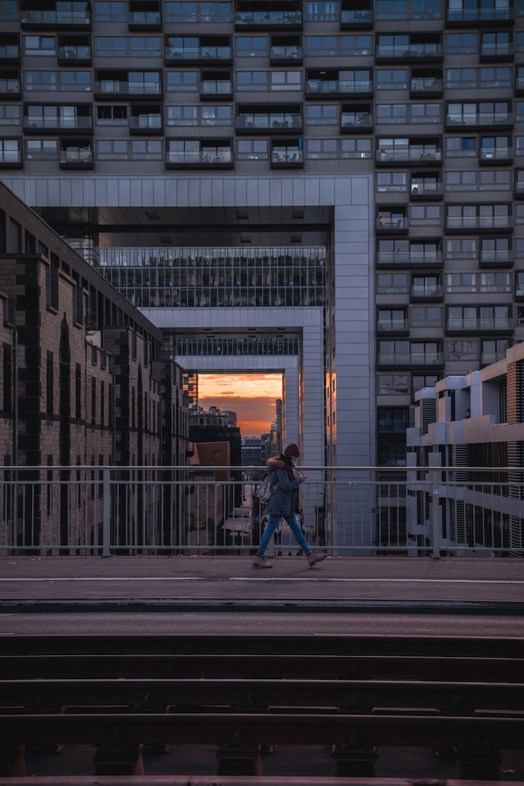 Pessoa caminhando sozinha em ponte urbana ao pôr do sol