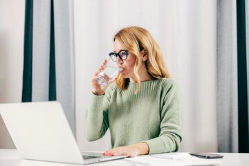 Remote worker drinking water at home office