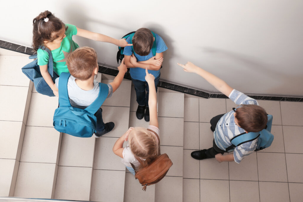 Ilustração de crianças em situação de bullying escolar, com um grupo excluindo um colega