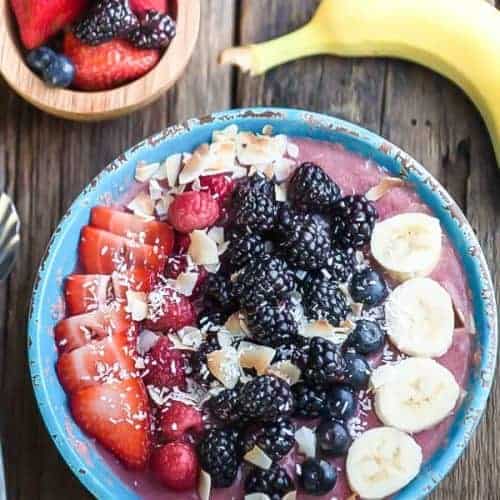 Colorful berry superfood smoothie bowl topped with fresh fruit and coconut