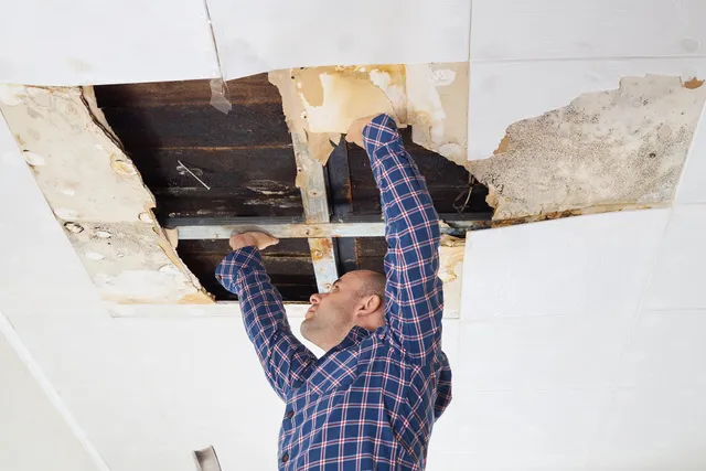 Restoration professional inspecting water-damaged ceiling and structural integrity after a leak
