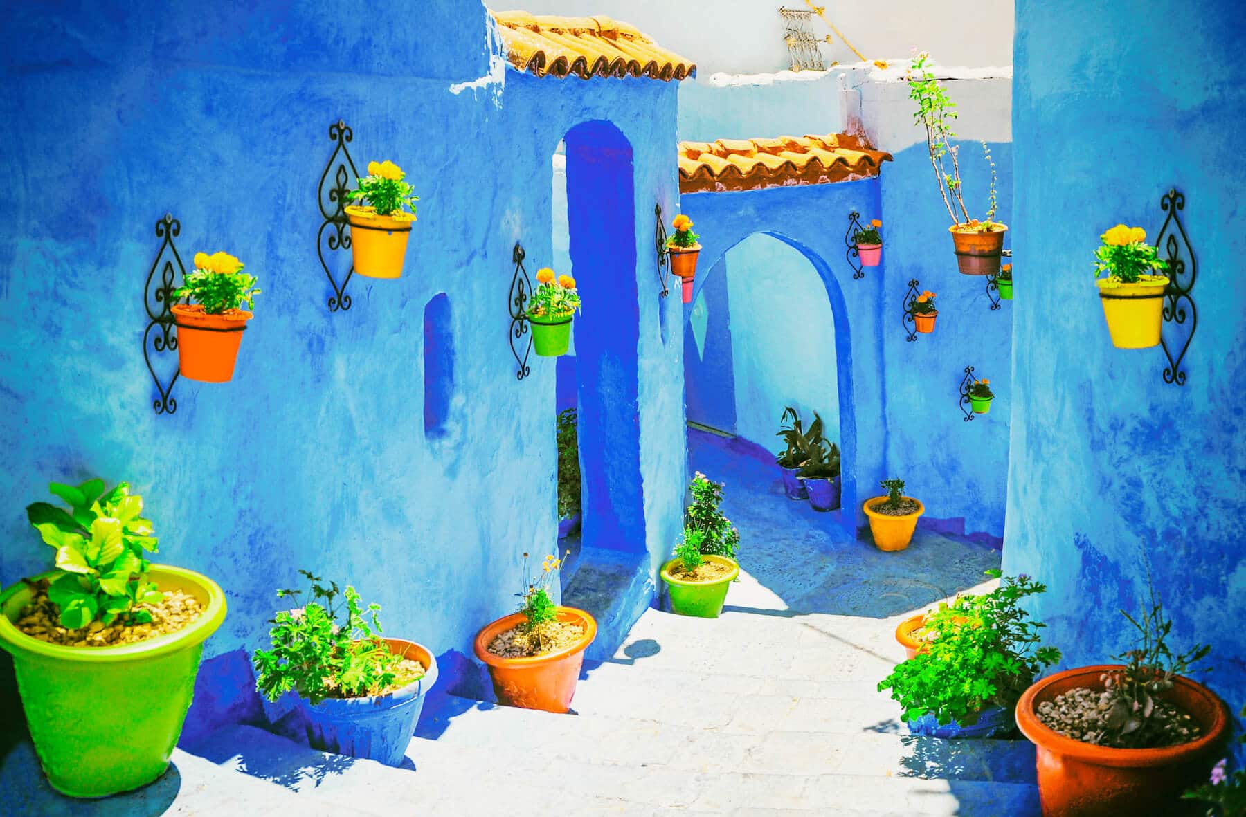 Cour intérieure bleue avec pots de fleurs colorés à Chefchaouen