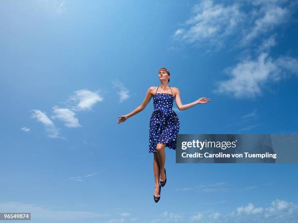 Model floating in blue sky polka dot dress