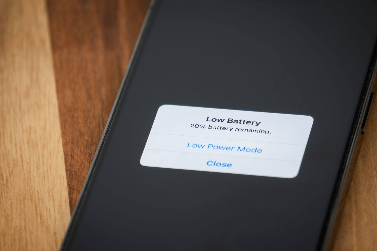 Person frustrated looking at phone with low battery warning